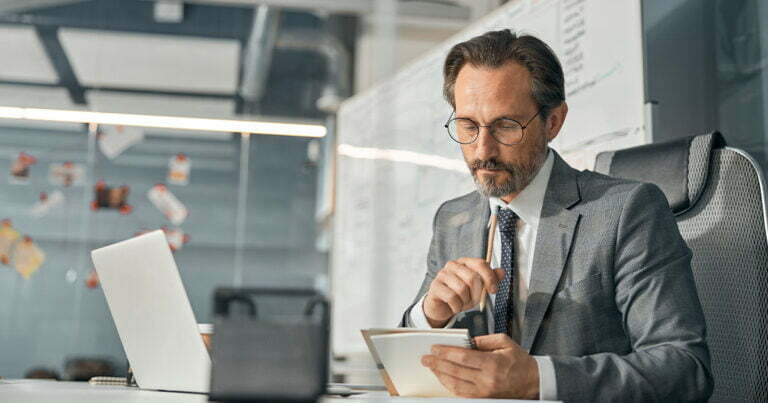 Older business man looking at notes while at desk