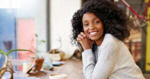 Happy lady with coffee sitting and smiling at you