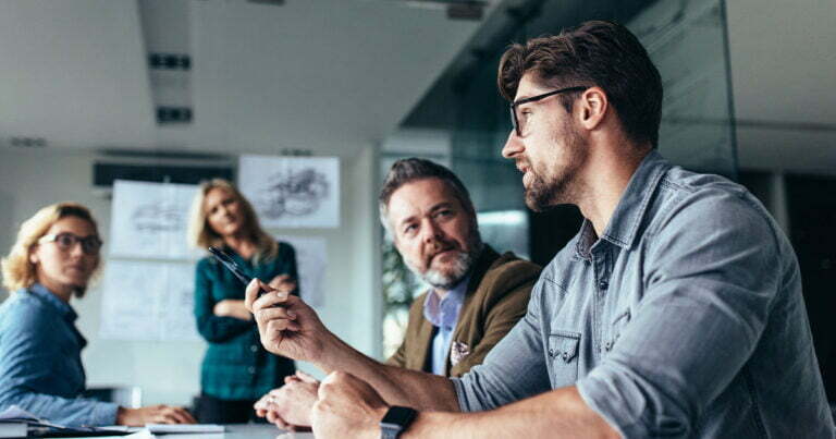 Man in business meeting talking to people at table