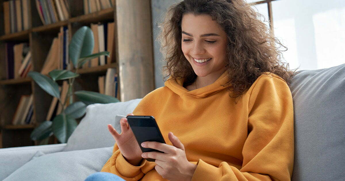 Happy girl in yellow hoodie on her phone