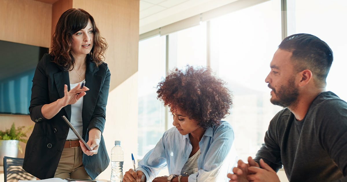 Lady explaining things to coworkers at table