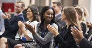 Happy business people clapping and looking at each other