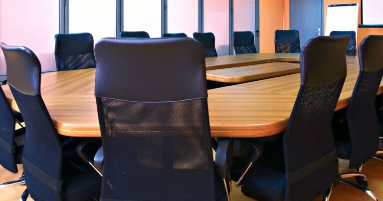 An empty board room table with chairs all around