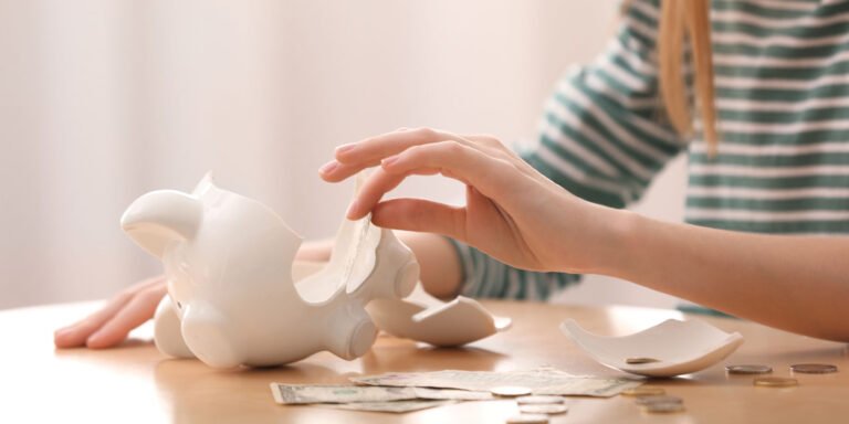 lady taking money out of a broken piggy bank