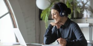 Happy lady with headphones on watching something on her laptop screen