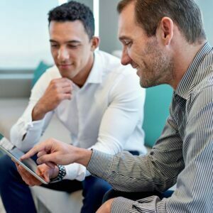 Two coworkers talking over information on ipad