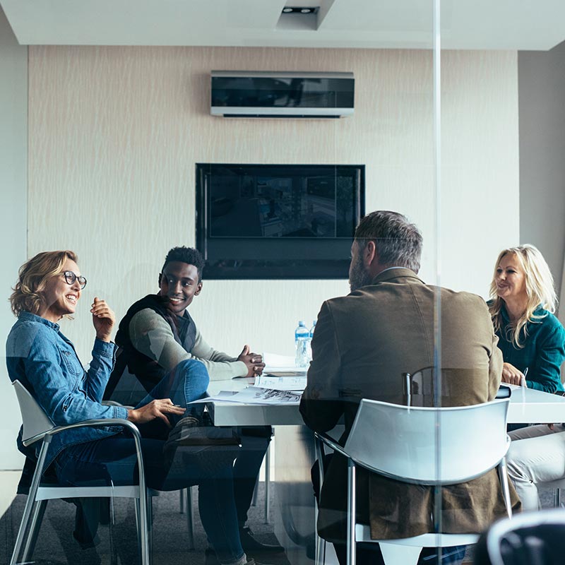 Coworkers talking happily at table while working