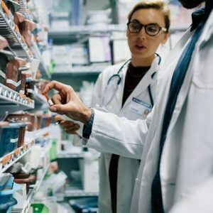 Two pharmacists working with shelves of medicine