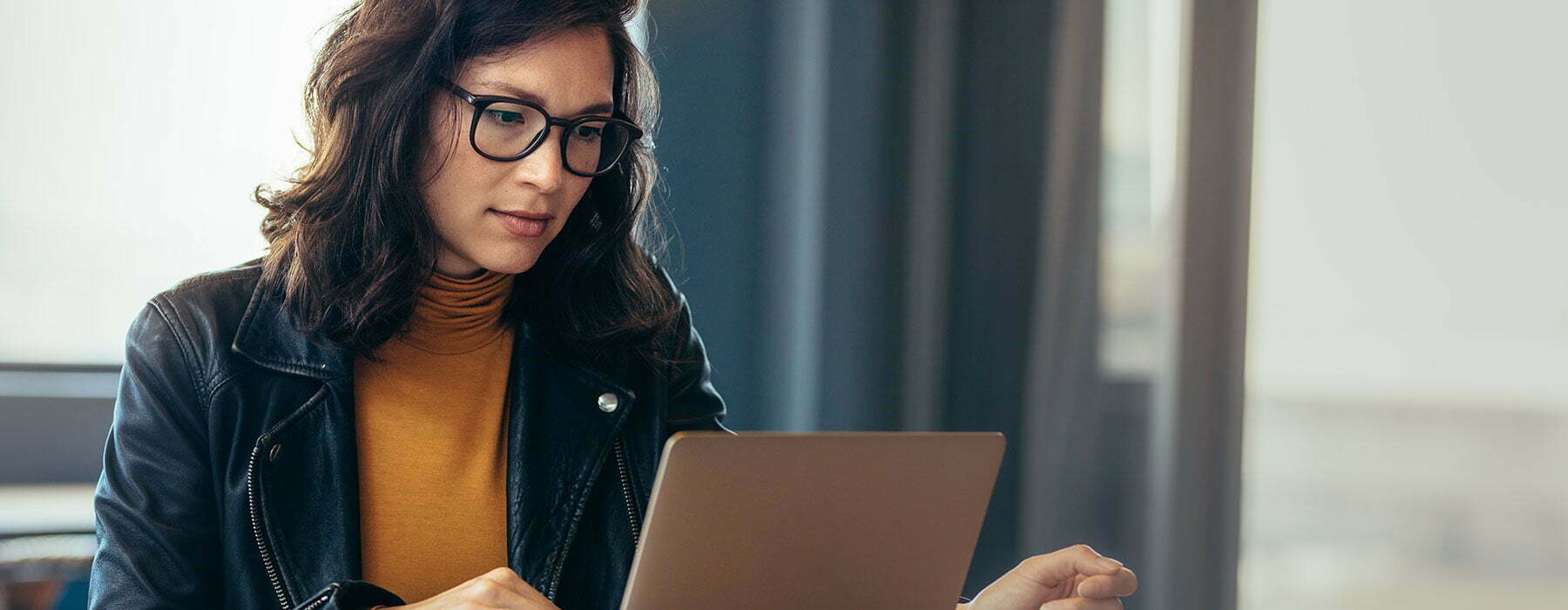 Lady in jean jacket focusing on laptop