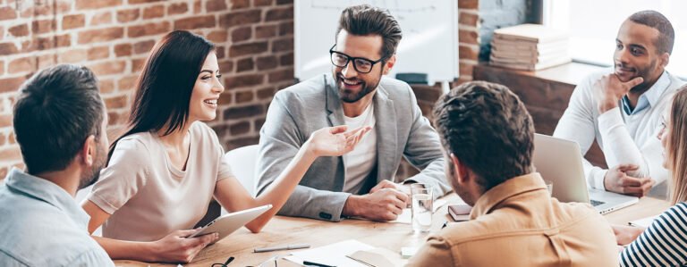 Coworkers talking happily at table while working