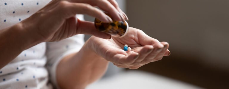 Person pouring out pills into hand from a pill bottle