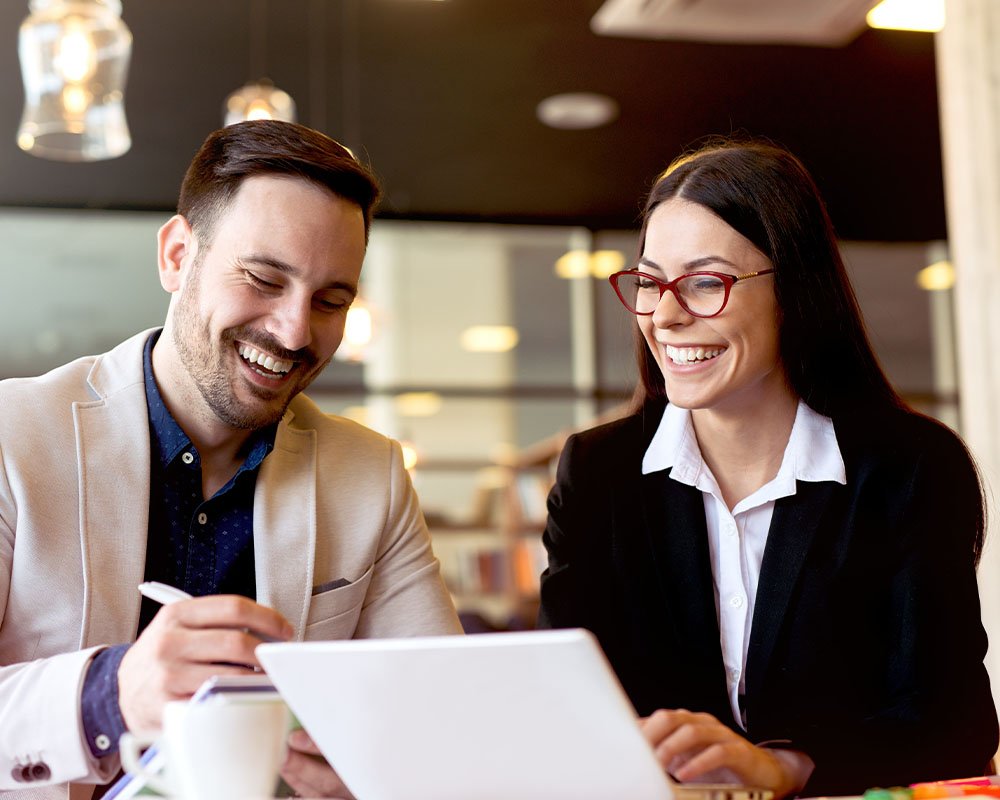 Two coworkers laughing and talking while working