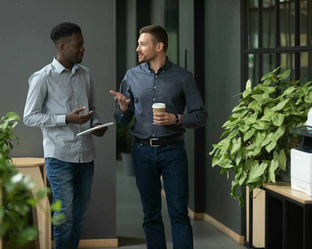 Two well dressed men talking while walking in office