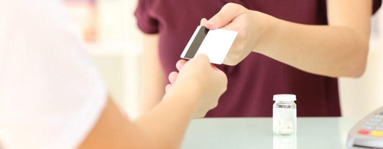 A person handing their card over to pharmacist for medicine