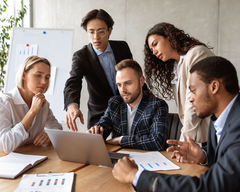 Business coworkers huddled around a laptop discussing its contents