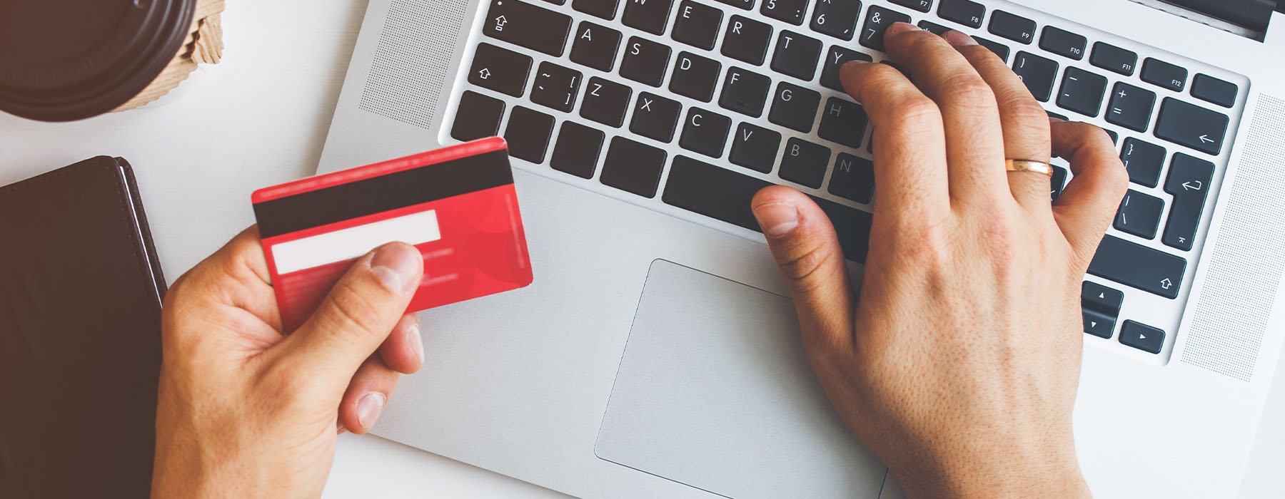 Person with card in hand typing on a computer with other hand