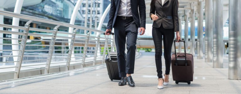 Two business people pulling suitcase along sidewalk