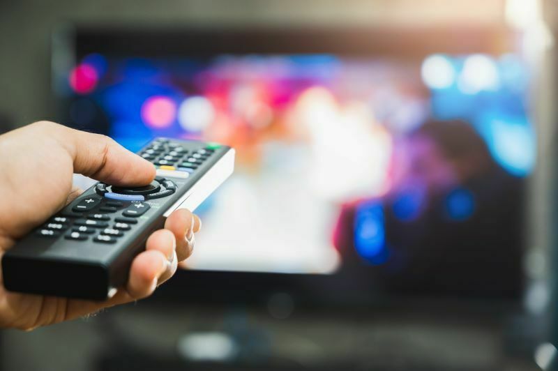 Person holding TV remote in front of TV